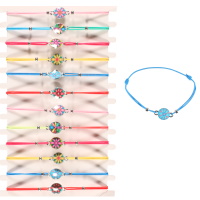 Bracelet élastique fantaisie avec cordon en coton et pastille ronde en métal argenté avec le motif de fleur en émail de couleur. 6 modèles différents.