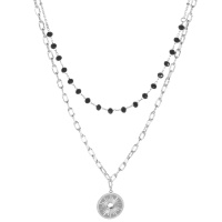 Collier double rangs composé d'une chaîne de 38 cm de long en acier argenté avec perles de couleur noire, ainsi qu'une chaîne de 45 cm de long en acier argenté et un pendentif rond surmonté d'un cristal. Fermoir mousqueton avec 5 cm de rallonge.