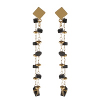 Boucles d'oreilles composées d'une puce en forme de losange en acier doré et d'une chaîne en acier doré avec perles carrés plates de couleur noire.