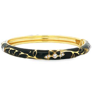 Ce bracelet jonc rigide allie le raffinement du métal doré à la profondeur d'un émail noir brillant. Son design organique et sophistiqué en fait un accessoire de choix pour sublimer un poignet avec une touche rétro-chic. Le corps du bracelet est recouvert d'un émail noir intense, parcouru de motifs filigranés dorés rappelant des volutes végétales ou des nervures délicates. Il est également orné de compositions florales stylisées serties de cristaux scintillants. Ces pierres apportent un éclat contrasté qui capte la lumière à chaque mouvement. Système de charnière discret permettant d'enfiler et de retirer le bijou avec facilité tout en assurant un maintien sécurisé au poignet.