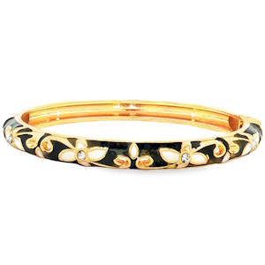 Ce bracelet se présente sous la forme d'un jonc rigide à la finition luxueuse. Il arbore un style émail noir et doré, offrant un contraste saisissant et sophistiqué. Le corps du bracelet est orné d'un motif floral continu et délicat. Des fleurs à quatre pétales en émail blanc crème sont disposées tout au long du cercle. Au cœur de chaque fleur se trouve un petit cristal étincelant, apportant une touche de lumière et d'éclat. Système de charnière discret permettant d'enfiler et de retirer le bijou avec facilité tout en assurant un maintien sécurisé au poignet.