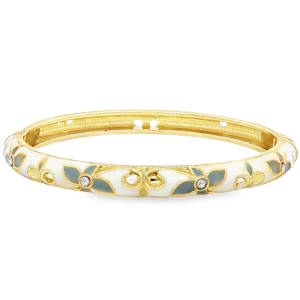 Le bracelet se présente sous la forme d'un jonc rigide en métal doré, dont la surface extérieure est richement travaillée. Son design évoque le style Art Nouveau ou les bijoux d'émail traditionnels, avec une touche de modernité. La structure est recouverte d'un émail blanc crème lisse qui sert de fond. Ce fond est agrémenté de motifs de feuilles délicates dans des tons de gris, créant un contraste doux et sophistiqué. Le bracelet est ponctué de petits cristaux scintillants incrustés au cœur des motifs floraux. Ces pierres apportent des points de lumière qui captent le regard à chaque mouvement du poignet. Système de charnière discret permettant d'enfiler et de retirer le bijou avec facilité tout en assurant un maintien sécurisé au poignet.