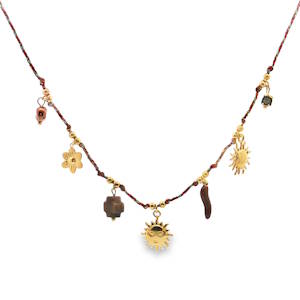 Ce collier à breloques unique en son genre marie l'artisanat traditionnel à une esthétique bohème chic. Le cordon tressé, ponctué de détails dorés délicats, sert de toile de fond à une série de breloques éclectiques. Un accessoire distinctif qui apporte une touche d'originalité à toute tenue. Fermoir mousqueton avec 5 cm de rallonge.