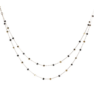 Collier double rangs composé d'une chaîne de 39 cm de long avec perles cubiques en acier doré et de perles cubiques de couleur noire, ainsi qu'une chaîne de 42 cm de long avec perles cubiques en acier doré et de perles cubiques de couleur noire. Fermoir mousqueton avec 5 cm de rallonge.