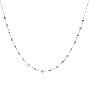 Collier composé d'une chaîne avec perles en acier doré, des perles cylindriques de couleur blanche et des perles rondes de couleur blanche. Fermoir mousqueton avec 5 cm de rallonge.
