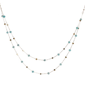 Collier double rangs composé d'une chaîne de 40 cm de long avec perles cubiques en acier doré et de perles cubiques de couleur bleue turquoise, ainsi qu'une chaîne de 42 cm de long avec perles cubiques en acier doré et de perles cubiques de couleur bleue turquoise. Fermoir mousqueton avec 5 cm de rallonge.