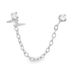 Apportez une touche de dynamisme et de modernité à votre style avec cette boucle d'oreille double piercing, conçue pour relier deux trous de perçage sur la même oreille. L'une des puces arbore un motif éclair en acier poli, symbole de force et d'énergie, surmonté d'un petit cristal scintillant. La seconde puce est ornée d'un cristal rond serti de quatre griffes, offrant une brillance pure et classique. Les deux éléments sont reliés par une fine chaîne à maillons forçat, créant un drapé délicat le long du lobe ou du cartilage. Entièrement réalisée en acier inoxydable, garantissant une haute résistance au ternissement et une excellente tolérance cutanée.