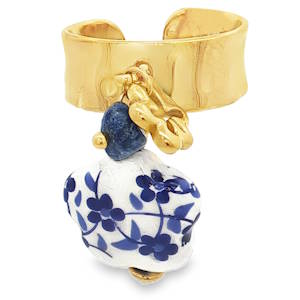 Affirmez votre style avec cette bague singulière qui marie l'éclat brut du métal à la délicatesse de l'artisanat d'inspiration azulejos. Un bijou de caractère, conçu pour celles qui aiment les pièces narratives et audacieuses. La pièce maîtresse est une pampille en céramique blanche aux contours organiques, ornée de motifs floraux bleu cobalt, rappelant le charme intemporel de la porcelaine ancienne. Le décor est complété par une perle de pierre naturelle bleue brute et un petit trèfle doré, apportant une touche de mouvement et de chance à l'ensemble. Sa structure ouverte à l'arrière permet de l'ajuster facilement à la taille de votre doigt, garantissant un confort optimal tout au long de la journée.