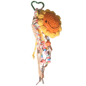 Porte-clés fantaisie avec des franges en textile multicolore, d'une fleur avec visage en textile jaune et orange, de perles multicolores et de cœurs multicolores.