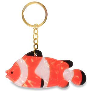 Ce porte-clés original capture l'esprit des récifs tropicaux avec un style à la fois ludique et élégant. Le pendentif représente un poisson-clown stylisé (rendu célèbre par Nemo), reconnaissable à ses larges bandes verticales. Équipé d'un anneau brisé classique et d'une courte chaîne à maillons en acier, le tout dans une finition dorée brillante qui apporte une touche de sophistication.