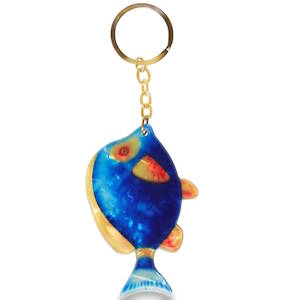 C'est un accessoire qui ne manque pas de peps ! Ce porte-clés, d'une esthétique à la fois rétro et ludique, mise tout sur la couleur et la texture. Le pendentif représente un poisson stylisé aux formes arrondies et généreuses. Son corps arbore un bleu électrique profond avec des effets marbrés qui rappellent les reflets de l’eau. Des touches contrastées de jaune doré et d'orangé viennent souligner les nageoires et le contour de l’œil, apportant une belle luminosité à l'ensemble. Le pendentif est suspendu à une chaîne à maillons et un anneau brisé en acier doré, ce qui renforce l'aspect qualitatif et élégant de l'objet.
