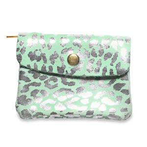 Ce petit porte-monnaie allie un style audacieux à un format ultra-pratique en cuir suédé doux au toucher, offrant une texture mate qui fait ressortir les détails brillants. Il arbore un imprimé léopard stylisé, revisité de manière moderne avec des taches argentées métallisées qui apportent un éclat festif. Le fond est d'un turquoise clair très frais, créant un contraste vibrant avec les reflets argentés.