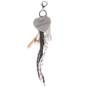 Ce porte-clés original et riche en textures semble être un cadeau personnalisé, mêlant des éléments sportifs et une touche d'affection. Au centre, un cœur en similicuir gris perle porte l'inscription Super maîtresse écrite dans une police simple et élégante. On retrouve une petite batte de baseball en bois clair accompagnée d'une mini balle de baseball blanche avec ses coutures rouges caractéristiques. Plusieurs lanières pendent sous le médaillon, rappelant des lacets de chaussures de sport (noirs et blancs à motifs géométriques) ainsi qu'un cordon en spirale noir.