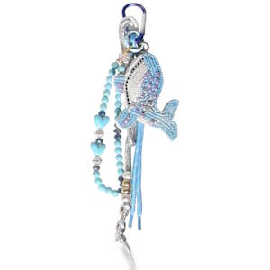 Ce porte-clés est un accessoire artisanal et fantaisie arborant un thème marin dans un dégradé de tons bleus, argentés et mauves. Il se distingue par son mélange de textures et de matériaux. La pièce maîtresse est une baleine en perles de rocaille, minutieusement brodée. Le corps mélange des perles bleu ciel, blanches et quelques touches de violet/mauve pour créer un effet de relief et de brillance. L'œil est marqué par une perle noire, et le ventre est représenté par des rangées de perles blanches horizontales.