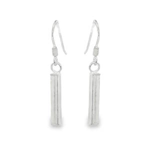 Arborez un style à la fois minimaliste et architectural avec ces boucles d'oreilles pendantes en argent 925/000. Leur design épuré mise sur la verticalité pour allonger le port de tête avec une élégance discrète. Chaque boucle présente un pendentif en forme de tube rectangulaire aux lignes nettes et aux surfaces polies, offrant un éclat subtil à chaque mouvement. Un accessoire intemporel qui complète aussi bien une tenue de bureau structurée qu'une robe de soirée moderne.