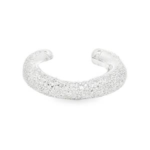 Cette bague d'oreille en argent 925/000 se distingue par sa finition givrée ou diamantée. Contrairement aux bijoux lisses et polis, sa surface est finement travaillée pour créer une multitude de facettes minuscules qui accrochent la lumière sous tous les angles, imitant le scintillement de la poussière d'étoiles ou du sable fin. Les extrémités de l'anneau sont arrondies et lisses, garantissant un glissement doux sur le cartilage de l'oreille sans irritation.