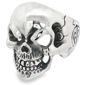 Cette bague imposante en argent arbore un style gothique, punk et résolument audacieux. Elle représente un crâne humain stylisé avec un travail de sculpture remarquable et un grand sens du détail. C'est un bijou de type chevalière, large et robuste, conçu pour être une pièce maîtresse (souvent portée sur le majeur, l'index ou le pouce).