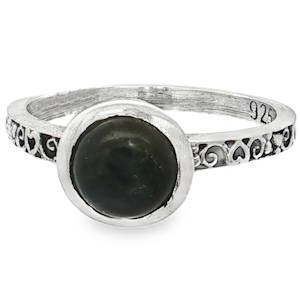 Cette élégante bague de style vintage et bohème se distingue par son allure intemporelle et ses détails soignés. La bague est sertie d'une pierre fine de forme cabochon (ronde et bombée, sans facettes). De couleur sombre (type labradorite), elle est solidement maintenue par un serti clos lisse et épuré. L'anneau est travaillé avec finesse, arborant une frise ciselée de motifs de cœurs et de volutes ajourés qui font tout le tour de la bague. Ce travail d'orfèvrerie apporte une touche romantique et délicate à l'ensemble.